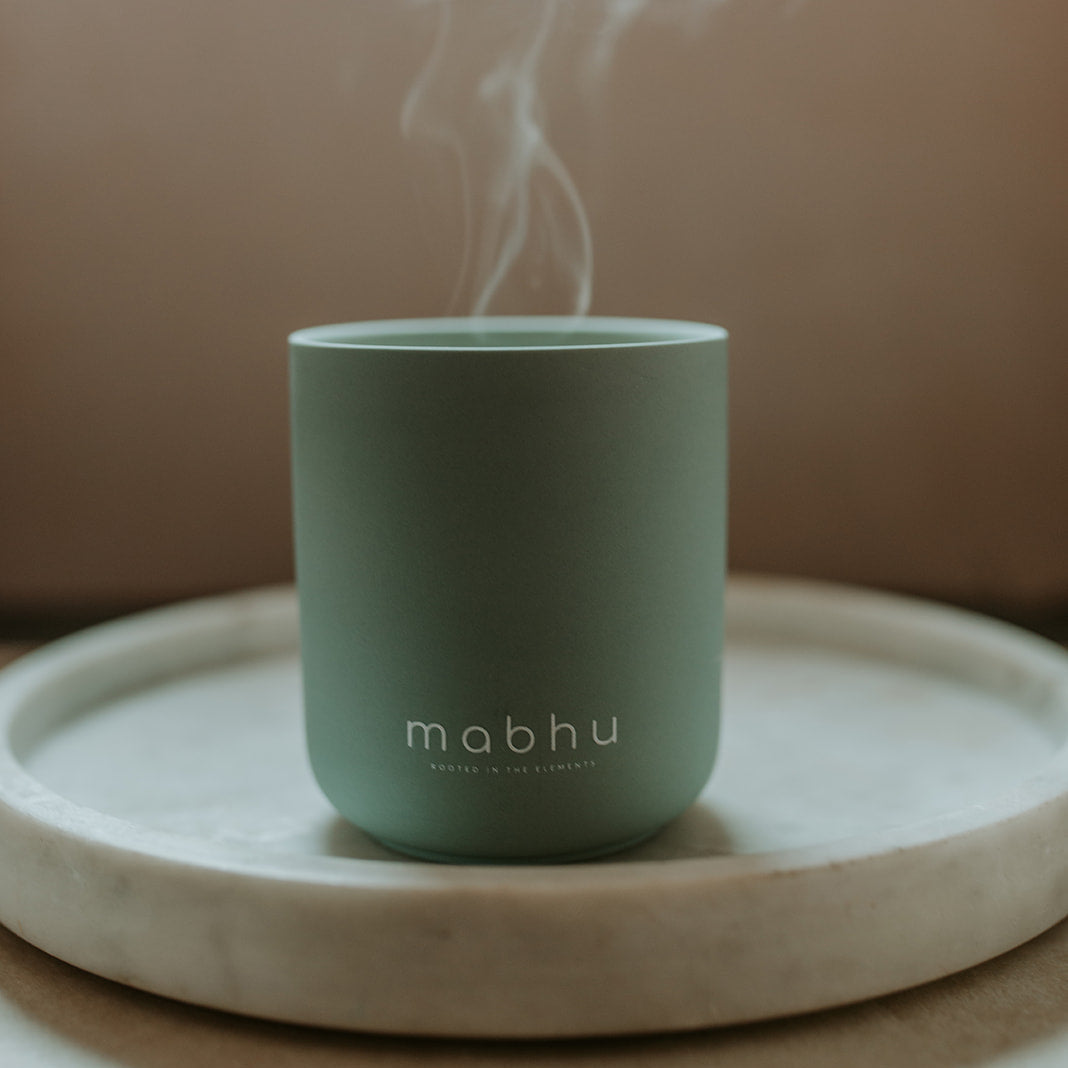 Green mug with steam on a beige background